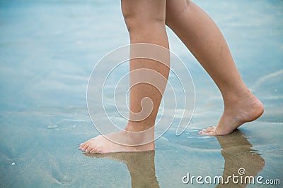 Women`s feet Was walking on a sandy beach at day time. Going forward alone Stock Photo