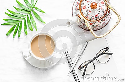 Women`s flat lay table with a cup of milk tea, teapot and clean empty notebook on a light background, top view. Stock Photo