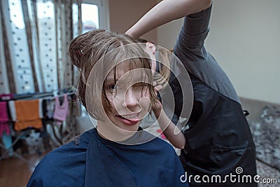 Women`s haircut at home. Hairdresser cuts a girl at home. Stock Photo