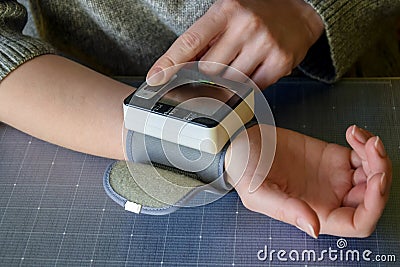 Women`s hands with blood pressure monitor. Preventing hypertension, concept of health care. Close-up. Stock Photo