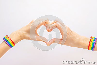 Women`s hands in a bracelet in rainbow colors LGBT folded in the shape of a heart. Stock Photo