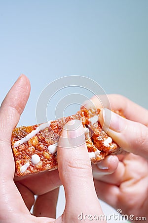 Women`s hands break a red protein bar with the taste of strawberries and raspberries. Healthy vegetarian snack, grain Stock Photo