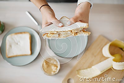 Women`s hands hold a peanut butter and banana sandwich Stock Photo