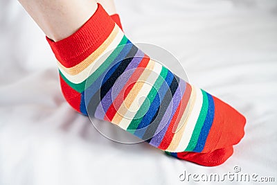 Women`s legs in socks several colors alternating, side stand on white fabric floor. Stock Photo