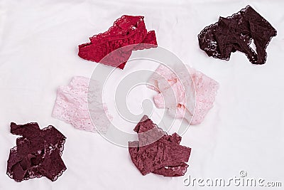 Women`s lingerie on white bed sheet. Many different lace bikini panties scattered on fabric Stock Photo