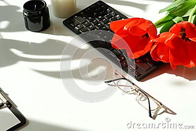 Women`s office desk .Female workspace with laptop, flowers red tulips, Stock Photo