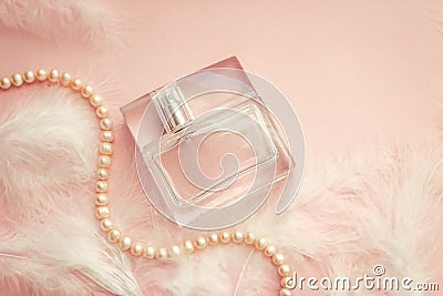 Women`s perfume on a delicate pink background with feathers Stock Photo