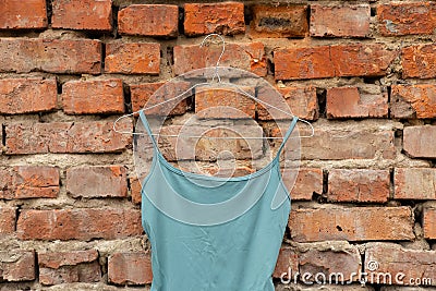 women's underwear blue t-shirt hangs on hangers on a brick old wall at home on the street, fashion Stock Photo