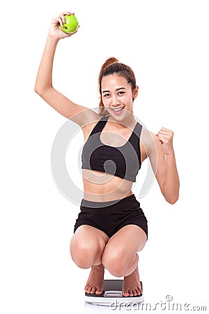 Women on scale cheering for achieving her weight loss goal Stock Photo