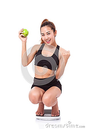 Women on scale cheering for achieving her weight loss goal Stock Photo