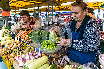 Women sell on the market ripe vegetables, onions, peppers, cucumber, greens Editorial Stock Photo