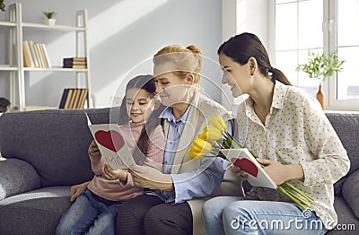 Women from several generations, who celebrate Women& x27;s Day at home together, look at their gifts. Stock Photo