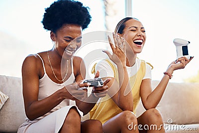 Women on sofa playing video game, laughing and relax in home living room together on internet with controller. Online Stock Photo