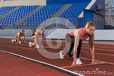 Women sprinters at starting position ready for race on racetrack. Stock Photo