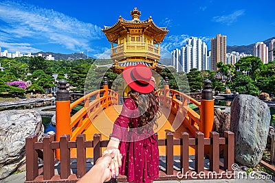 Women tourists holding man`s hand and leading him to Golden Pavilion in Nan Lian Garden near Chi Lin Nunnery temple, Hong Kong Stock Photo