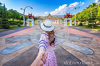 Women tourists holding man`s hand and leading him to Ho kham luang northern thai style in Royal Flora ratchaphruek in Chiang Mai,T Stock Photo