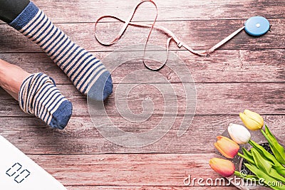 Women wearing strip sock sitting with white digital scale and measuring tape on the wooden background Stock Photo