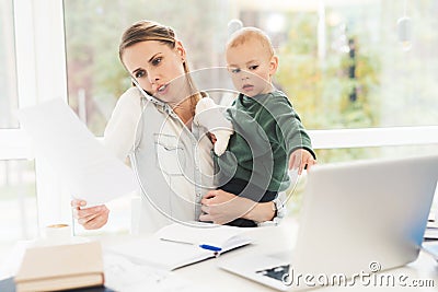 A woman works during maternity leave at home. A woman works and cares for a child at the same time. Stock Photo