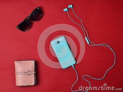 Women& x27;s accessories are lined on a red background. Smartphone, headphones, wallet, sunglasses. Flat lay Stock Photo