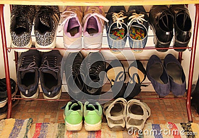Womens, mens and childrens shoes are stored on an open shelf. Green Childrens Sneakers Stock Photo