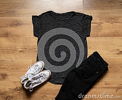 Womens Black marl effect T shirt mock up on wooden backdrop with jeans and sneakers Stock Photo