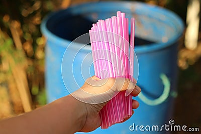Women& x27;s hand holding pink plastic tube To throw away the trash Concepts of using plastic tubes to reduce global warming Stock Photo