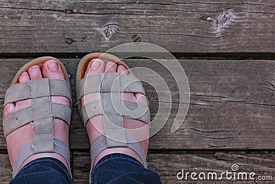 womens white feet standing in sandles on old wooden boards Stock Photo