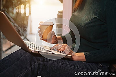 Womman using laptop and typing on laptop and holding coffee Stock Photo