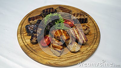 A wonderful meat dish cooked on a barbecue with ribs juicy and leaves of lettuce and laid out on wood Stock Photo