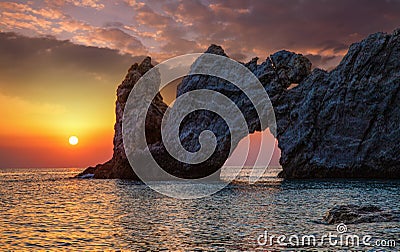 Wonderful rock with a hole on the sea at sunset Stock Photo
