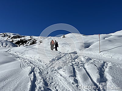 Wonderful winter hiking trails and traces in the fresh alpine snow cover of the Swiss Alps and over the tourist resort of Arosa Editorial Stock Photo