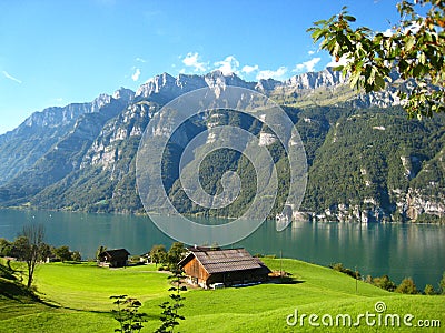 Wonderfully panorama view with a turquoise blue swiss lake with snow-covered mountains and wooden houses Stock Photo