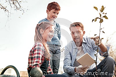 Wondering children smiling while father explain how growing tree Stock Photo