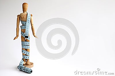 Wood mannequin holding and wrapped in a blue tape measure for a weight loss and plastic surgery beauty concept Stock Photo