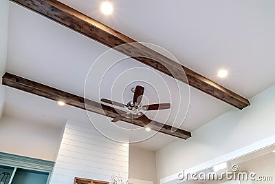 Wood beams and recessed bulbs with ceiling fan and lights at the center Stock Photo