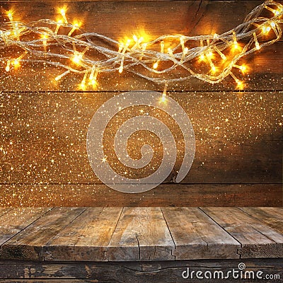 Wood board table in front of Christmas warm gold garland lights on wooden rustic background. filtered image. selective focus. Stock Photo