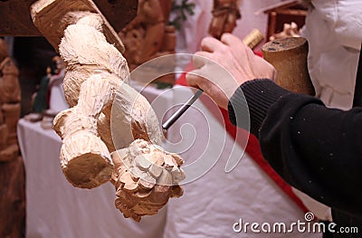 Wood carver's hands sculpting a wooden angel Stock Photo