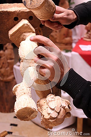 Wood carver's hands sculpting a wooden angel in workshop Stock Photo