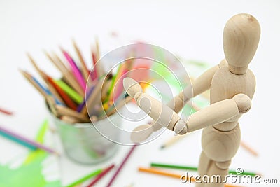 Wood doll, colored pencils and abstract paints on white background Stock Photo