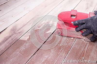 Wood floor polishing maintenance work by grinding machine. Men`s hands with gloves make repairs at home. Grinding Stock Photo