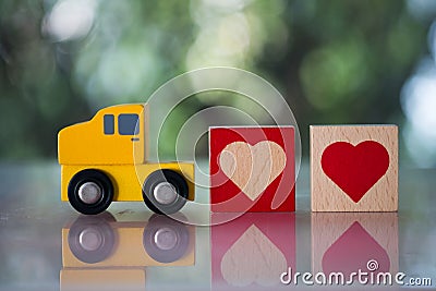 Wood heart follow yellow toy car for sending to couple. The concept of love Stock Photo