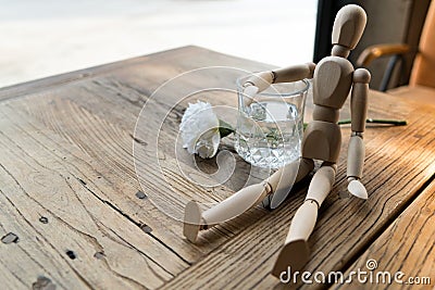 A wood man is sitting and put the arm on the glass of water Stock Photo