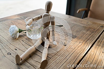 A wood man is sitting and put the arm on the glass of water Stock Photo