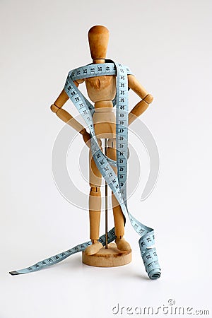 Wood mannequin holding and wrapped in a blue tape measure for a weight loss and plastic surgery beauty concept Stock Photo