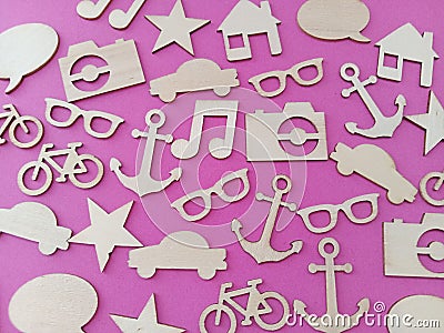 Wood shapes stars bikes anchors music notes cars on a pink background Stock Photo