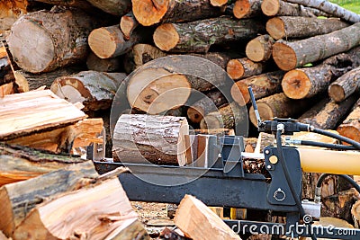 Wood splitter between heap of split wood and pile of logs Stock Photo