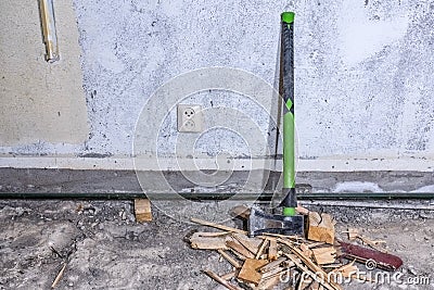 Wood splitting maul stands at concrete wall on demolished room floor, close up view Stock Photo