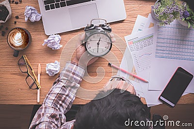 Wood table with businessman holding alarm clock, late payment Stock Photo