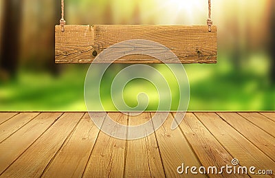 Wood table with hanging wooden sign on green forest blurred background Stock Photo