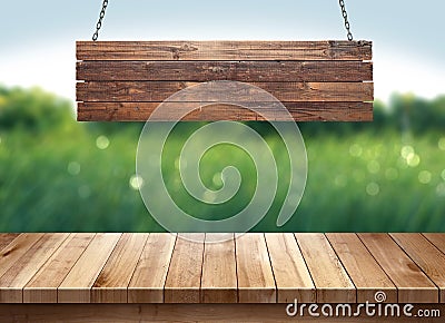 Wood table with hanging wooden sign on green nature blurred background Stock Photo